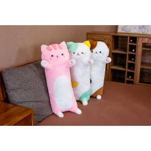 Na szarej sofie w małym salonie z brązową podłogą stoją 3 pluszowe poduszki z wizerunkiem dużego kota, jedna jest różowa, druga zielona, a trzecia brązowa