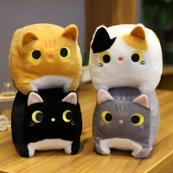 Cztery pluszowe kwadratowe koty na drewnianym stole. Żółty kot na czarnym kocie i biały kot na szarym kocie.